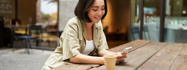 写真 カフェで携帯電話を使っている若い女性