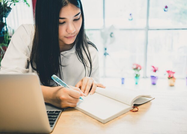 写真 テーブルの上で携帯電話を使っている若い女性