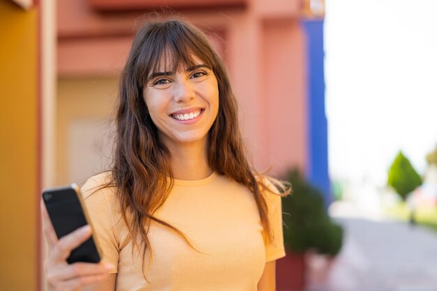 Young woman using mobile phone at outdoors smiling a lot