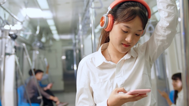 Giovane donna che utilizza il telefono cellulare sul treno pubblico