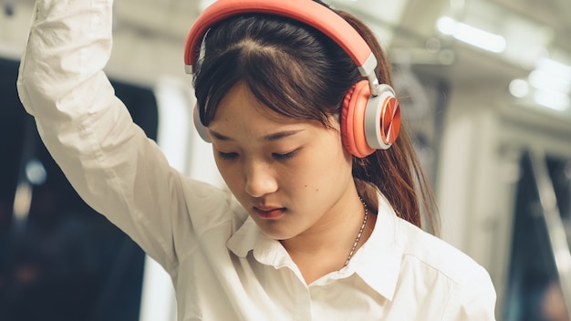 Giovane donna utilizzando il telefono cellulare sul treno pubblico