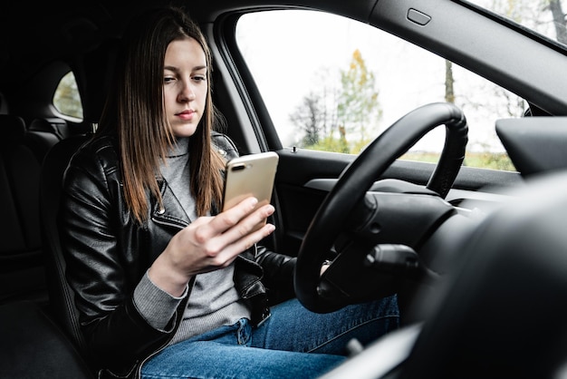 車の運転中に携帯電話を使用している若い女性。