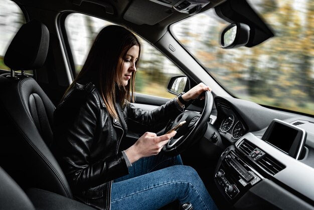 Giovane donna che utilizza il telefono cellulare durante la guida dell'auto.