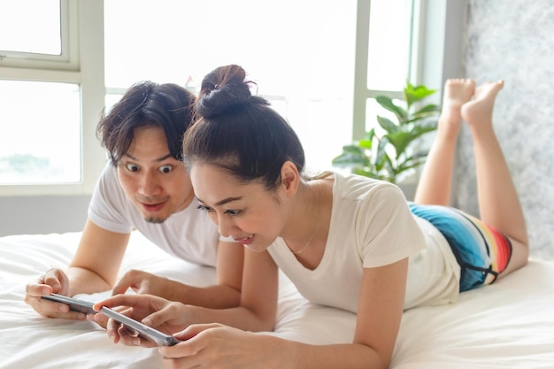 Young woman using mobile phone while relaxing on bed at home