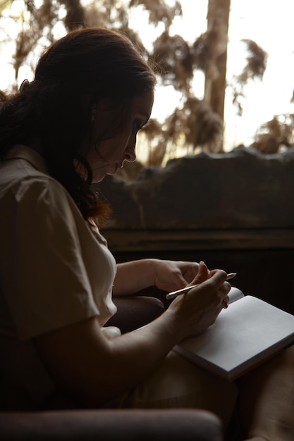 Photo young woman using mobile phone while sitting on bed at home