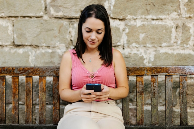 Foto giovane donna che utilizza il telefono cellulare mentre è seduto su una panchina al park