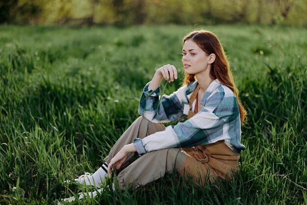 Young woman using mobile phone while sitting on field