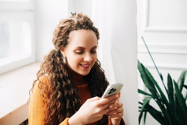 Photo young woman using mobile phone while sitting at home