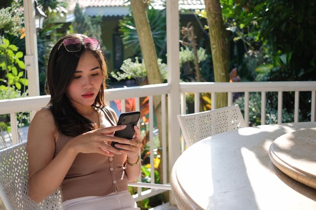 写真 カメラに向かって座っているときに携帯電話を使っている若い女性