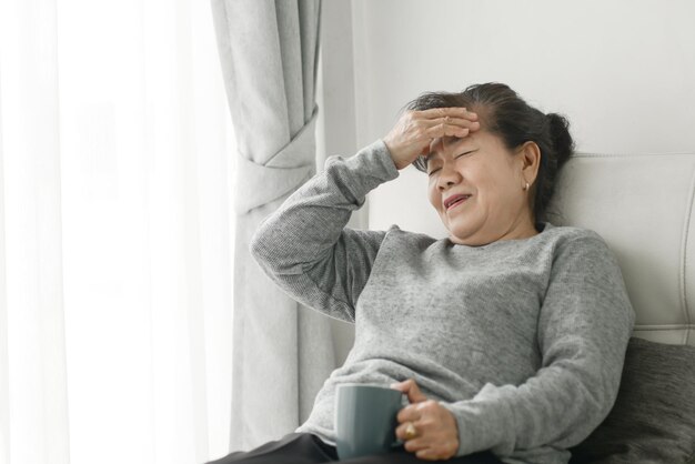 写真 家の窓に座って携帯電話を使っている若い女性