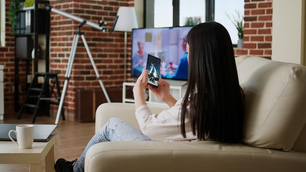 Young woman using mobile phone while sitting on sofa at home