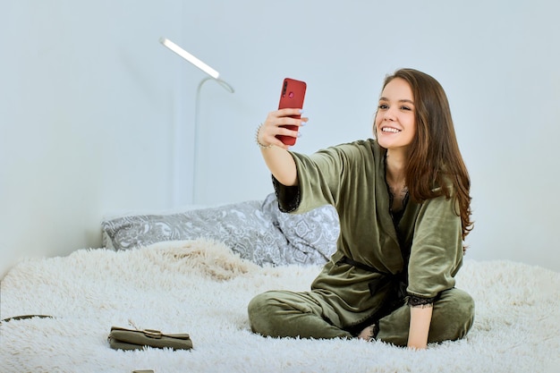 家のソファに座って携帯電話を使っている若い女性