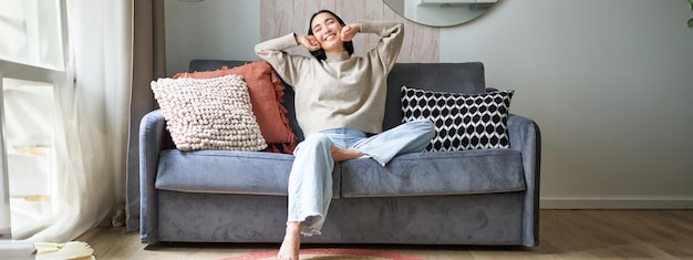 Photo young woman using mobile phone while sitting on sofa at home