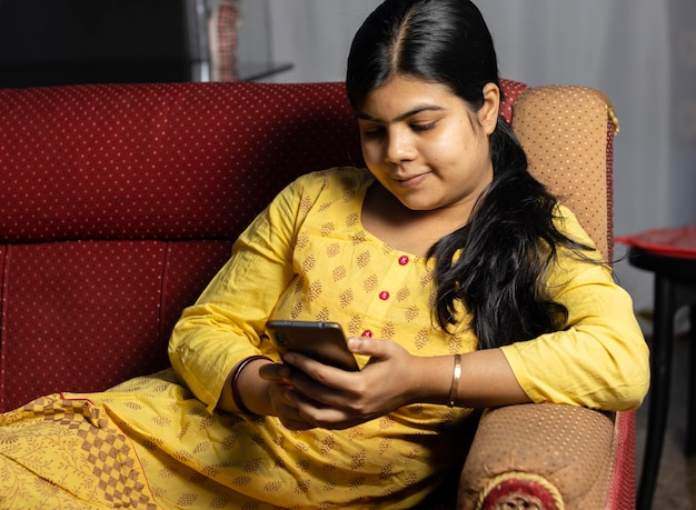 Young woman using mobile phone while sitting on sofa