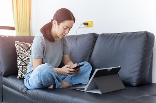 Young woman using mobile phone while sitting on sofa