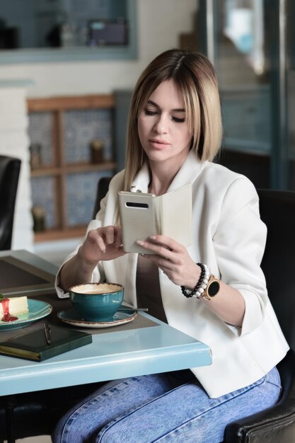 Photo young woman using mobile phone while sitting on table