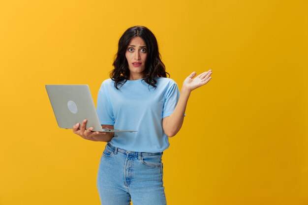 Young woman using mobile phone while standing against yellow background