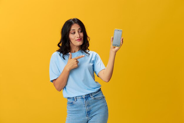 Young woman using mobile phone while standing against yellow background