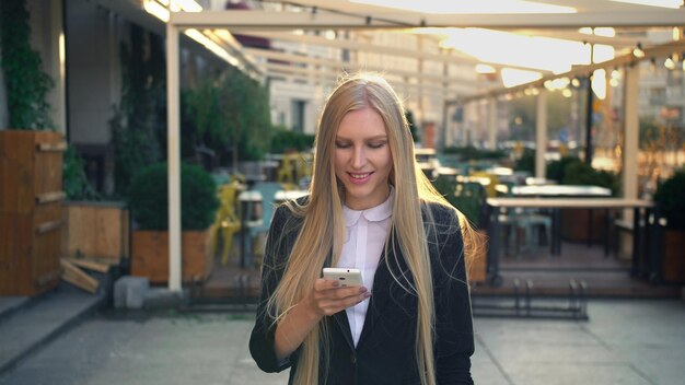 写真 街に立っている間携帯電話を使っている若い女性