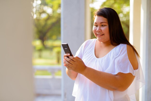 Young woman using mobile phone while standing on mirror