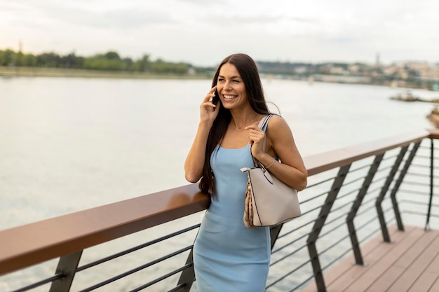 Young woman using a mobile phone while walking on the river promenade