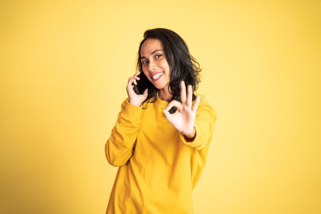 Young woman using mobile phone with thumbs up