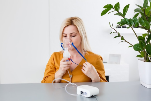 Young woman using nebulizer for asthma and respiratory diseases at home