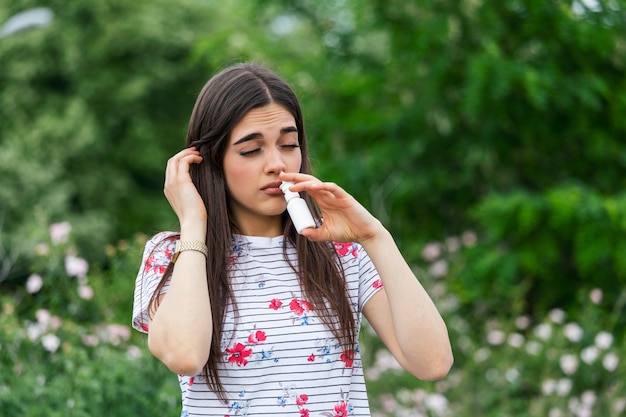 Giovane donna che usando spray per naso per le sue allergie di polline ed erba