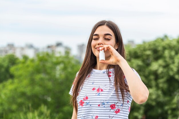 花粉や草のアレルギーに点鼻薬を使用している若い女性