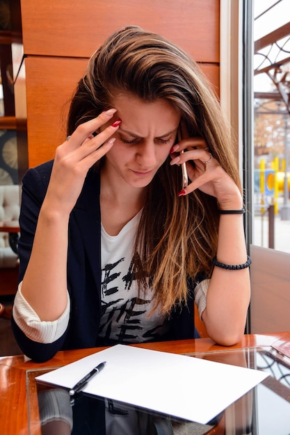 カフェで電話を使っている若い女性