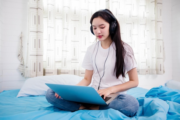 Young woman using phone while sitting on bed