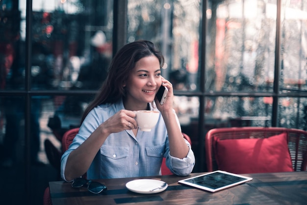 カフェに座って電話を使っている若い女性
