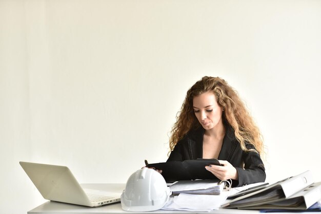 Young woman using phone while sitting on laptop