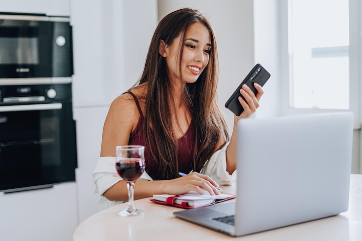Photo young woman using phone while sitting on laptop