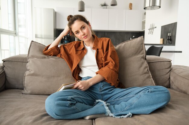 Photo young woman using phone while sitting on sofa at home