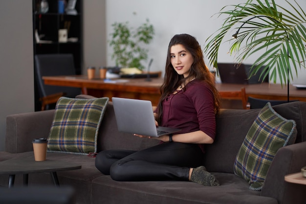 Young woman using phone while sitting on sofa at home