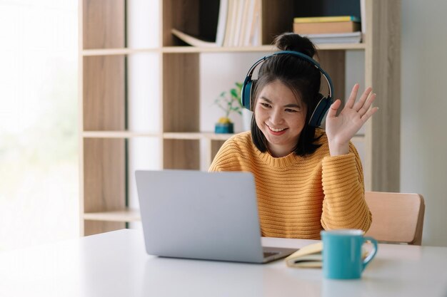 自宅のテーブルに座って電話を使っている若い女性