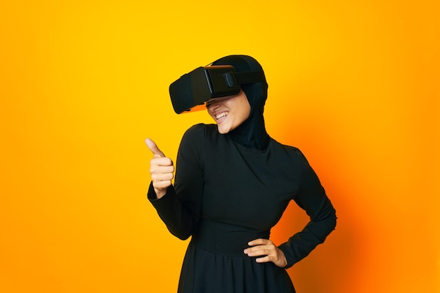 Young woman using phone while standing against orange background