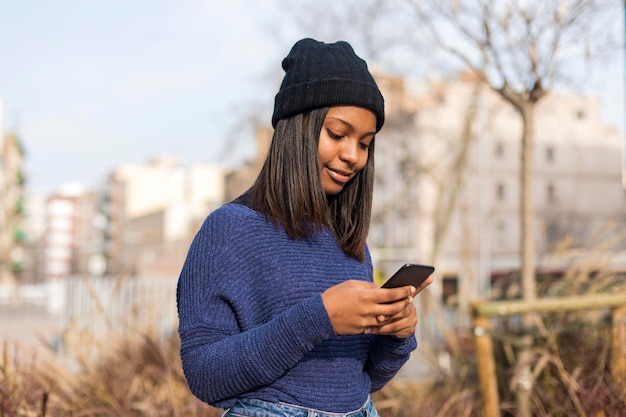 Foto giovane donna che usa il telefono in piedi all'aperto