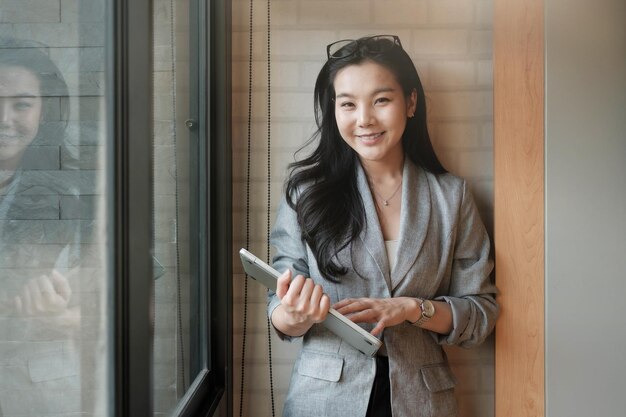 Photo young woman using phone while standing on window