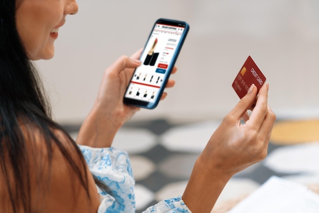 Foto giovane donna che utilizza smarpthone con carta di credito per internet banking online shopping e-commerce tramite gateway di pagamento online a casa shopping online moderno e conveniente con carta di debito blithe