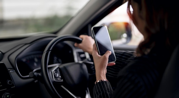 Foto giovane donna che utilizza il telefono cellulare intelligente in auto durante la guida