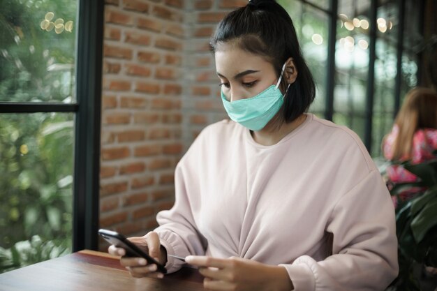 Photo young woman using smart phone on table at window