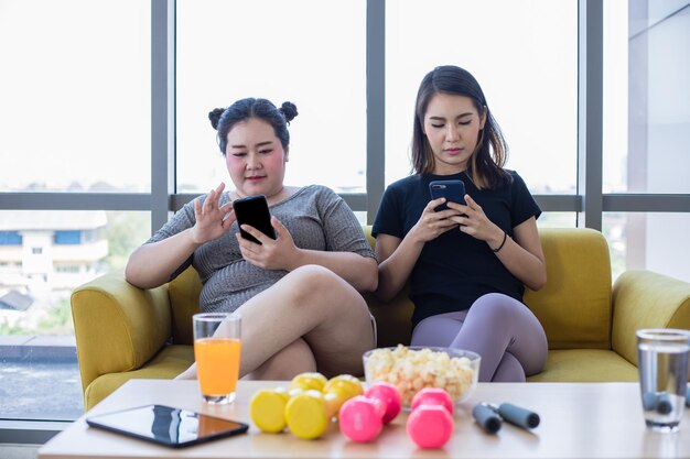 Young woman using smart phone while sitting on laptop