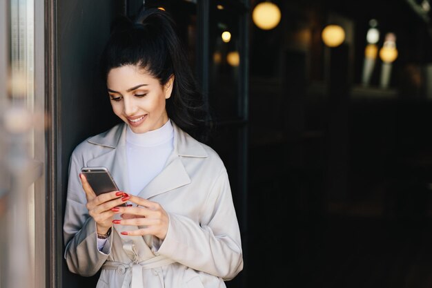 写真 家に立ってスマートフォンを使っている若い女性