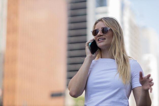 Young woman using a smartphone at day time with city view landscape in the background high quality photo mobile phone technology urban concept person