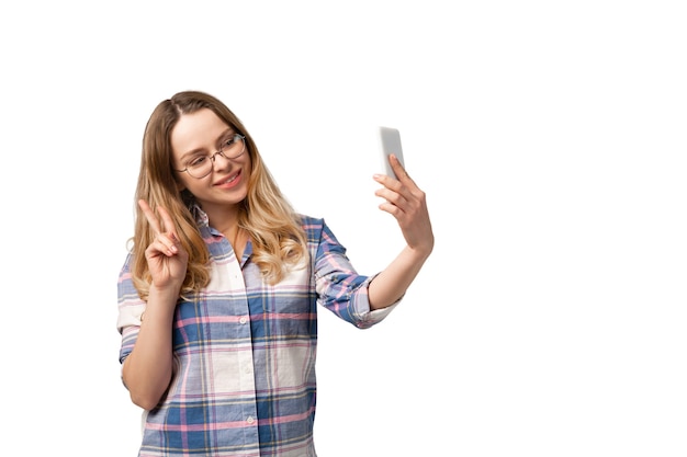 Young woman using smartphone, devices, gadgets isolated on white studio wall