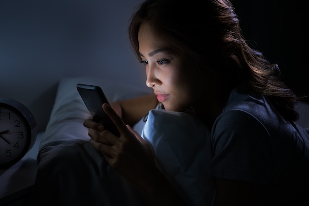 Young woman using a smartphone in her bed at night