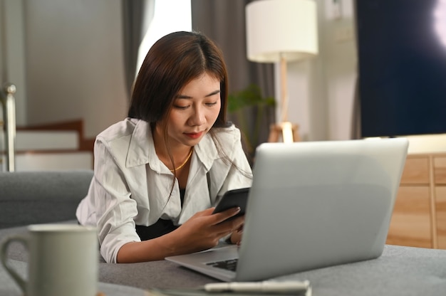 自宅でスマートフォンを使用して若い女性