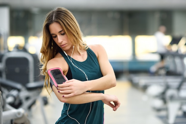 ジムでスマートフォンを立てている若い女性